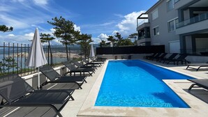 Un'area piscina moderna con lettini e vista sul mare.