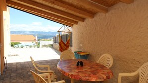 An outdoor patio with a round table and chairs, a hammock, and a view of the landscape. - Apartment Ivo by Interhome (Polje)
