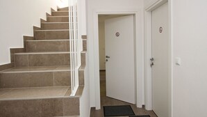 A staircase leading to a door with a 'no entry' sign, a doormat, and a light switch on the wall. - Apartment Ivo by Interhome (Polje)