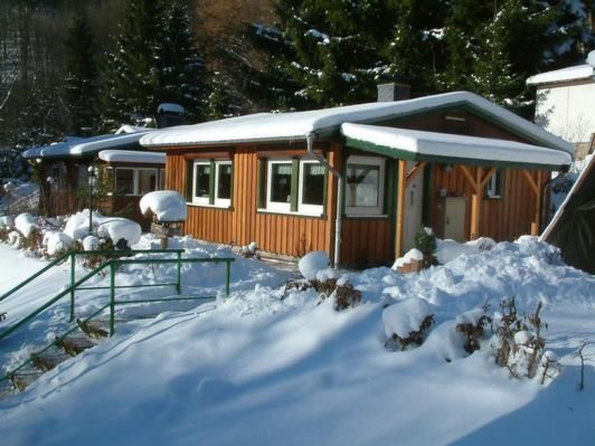 A wooden cabin with a snow-covered roof, surrounded by snow.