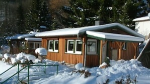 Une cabane en bois dont le toit est recouvert de neige, entourée de neige.