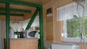 Une cuisine compacte équipée d’un four à micro-ondes, d’un petit îlot central avec un évier et d’une chaise.
