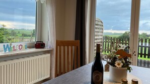 Ein Zimmer mit Blick auf eine grüne Landschaft, eine Weinflasche, ein Willkommensschild und ein Radio auf einem Fensterbrett.