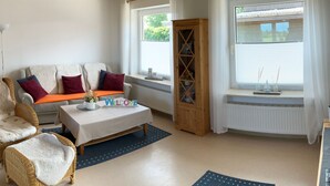 Un salon confortable avec un canapé, deux fauteuils, une table basse et un meuble.