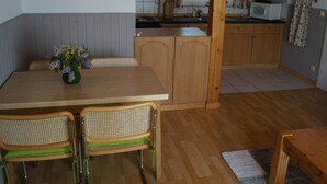 Una cucina con mobili in legno, un forno a microonde e un'area pranzo con tavolo e sedie.