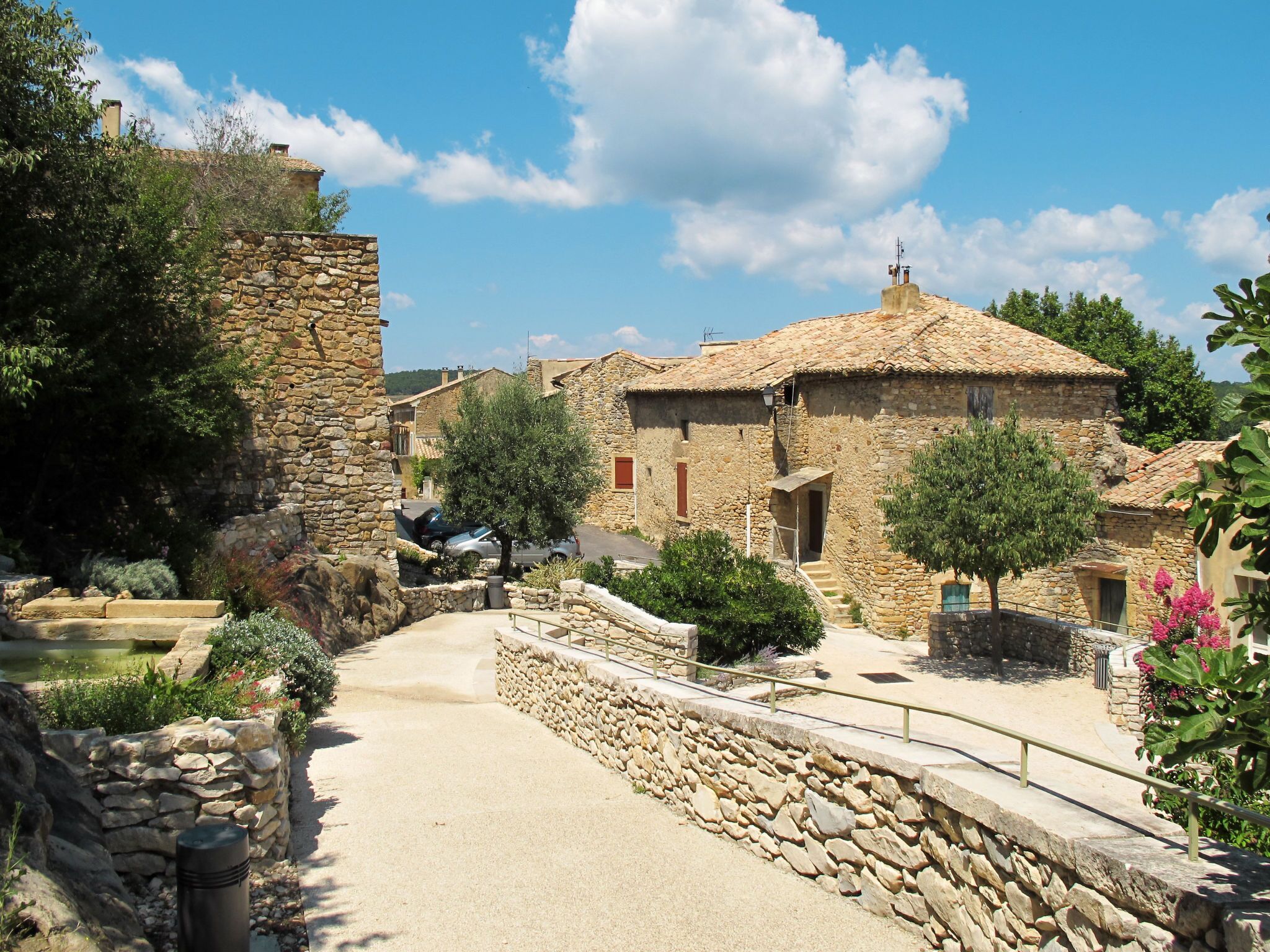 A stone pathway leading to traditional stone buildings with a clear sky above.