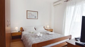Quarto de hotel com cama, mesas de cabeceira, televisão e ar condicionado.