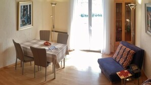 A dining area with a table and chairs, a sofa, and a bookshelf. - Casa Argo by Interhome (Ronco sopra Ascona)