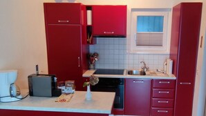 A compact kitchen with red cabinets, a sink, and a small countertop. - Casa Argo by Interhome (Ronco sopra Ascona)
