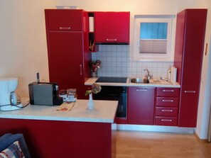 A compact kitchen with red cabinets, a sink, and a small countertop. - Casa Argo by Interhome (Ronco sopra Ascona)