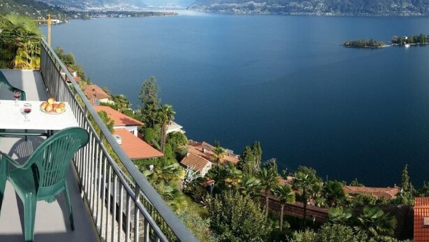A terrace with a table and chairs overlooking a lake with mountains in the background. - Casa Argo by Interhome (Ronco sopra Ascona)