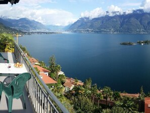 A terrace with a table and chairs overlooking a lake with mountains in the background. - Casa Argo by Interhome (Ronco sopra Ascona)