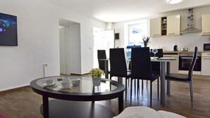 Eine moderne Küche mit Essbereich, darunter ein runder Tisch mit Stühlen und eine Couch.