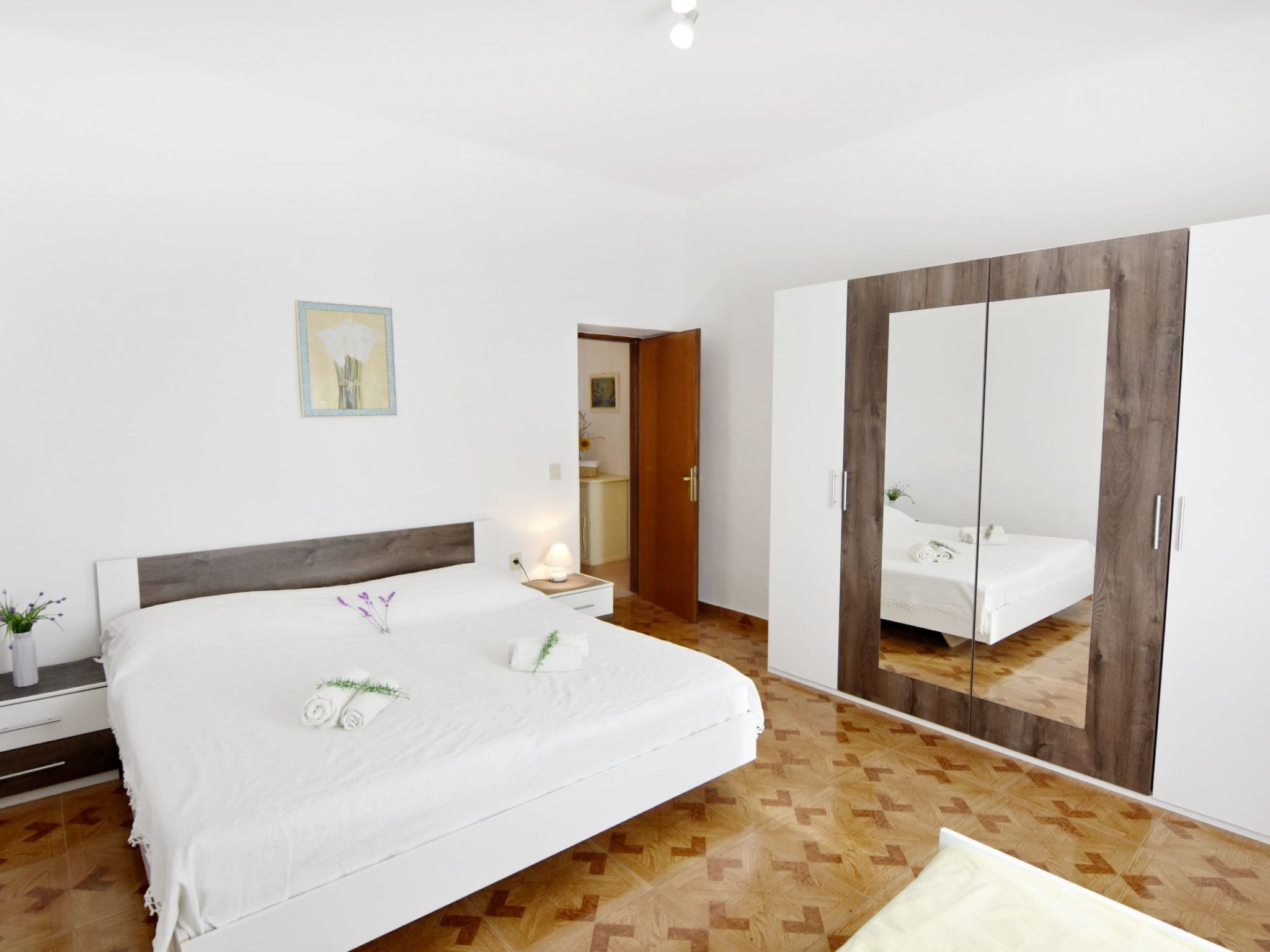 A hotel room with a large bed, a wardrobe, a bedside table, and a nightstand.