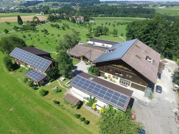 Een landelijk gelegen pand met meerdere gebouwen, waaronder een hoofdgebouw met een schuin dak en zonnepanelen.