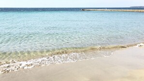 A beach with clear water, a sandy shore, and a breakwater in the distance. - Gilda Punta B4 by Interhome (Umag)
