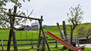 Une aire de jeux avec un toboggan, des balançoires et une clôture en bois.