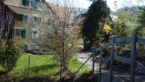Un barrio residencial con una casa, un portón de madera y un patio cubierto de césped.