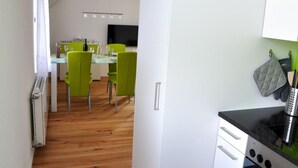 Eine moderne Küche mit weißen Schränken, einer schwarzen Arbeitsplatte und einem grünen Stuhl.