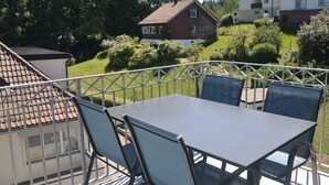 Eine Terrasse mit Tisch und Stühlen, umgeben von einem Metallgeländer.
