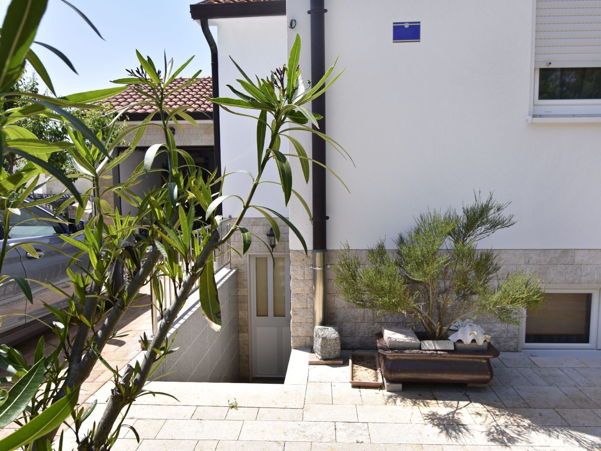 Ein Gebäude mit einem Ziegeldach, einer weißen Wand und einem kleinen Garten mit Pflanzen und einer Bank.