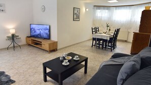 A living room with a TV, a dining table with chairs, a sofa, and a coffee table. - Geräumige Kellerwohnung in der Nähe von Umag by Interhome (Umag)