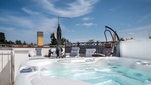 Un jacuzzi en la azotea con sillones de descanso y una pérgola.