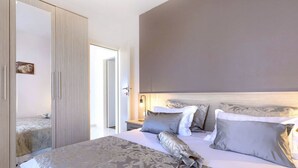 Un dormitorio con una cama grande, un armario y una mesita de noche con una lámpara.