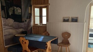 A wooden dining table with a blue tablecloth, two wooden chairs, and a painting on the wall. - Chesa alb sco'l floc by Interhome (S-chanf)
