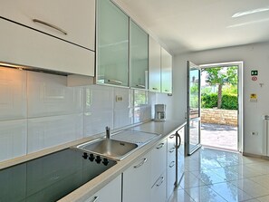 A modern kitchen with white cabinets, a stainless steel sink, and a built-in stove.