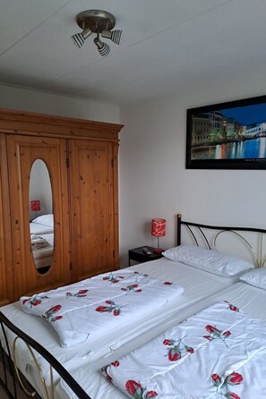 Ein Schlafzimmer mit einem Bett, einem Holzschrank, einem Nachttisch, einer Lampe und einem Stadtbild.