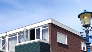 En toetagers bygning med fladt tag, store vinduer og en balkon.