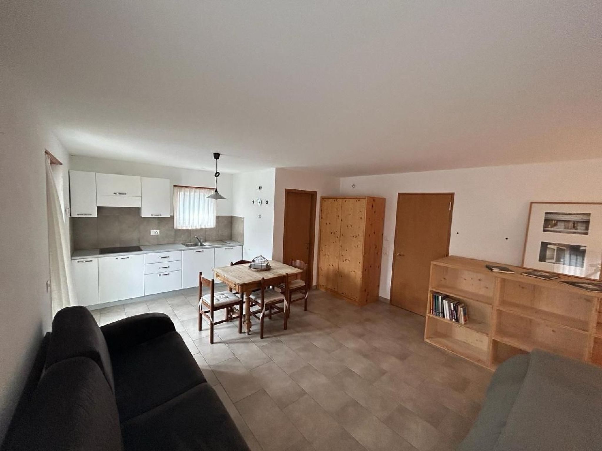 Ein kompakter Wohnbereich mit Küchenzeile, Essbereich und einer Sitzecke mit Sofa und Bücherregal.