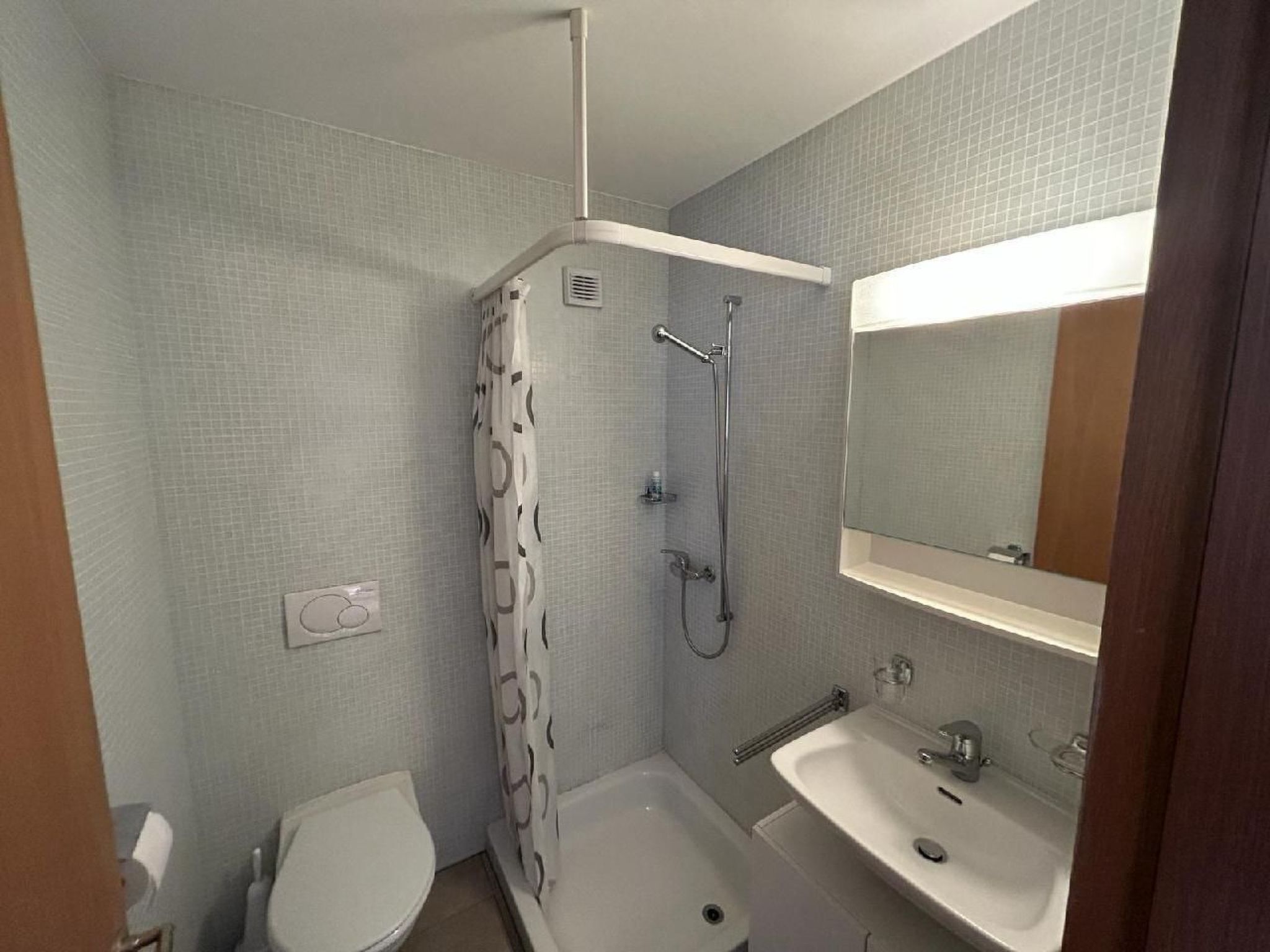 A small bathroom with a shower, toilet, and sink.