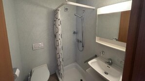 Een kleine badkamer met douche, toilet en wastafel.