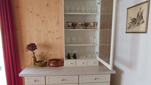 A kitchen with a white cabinet, a red curtain, and a vase with flowers. - in Borgonovo by Interhome (Borgonovo)