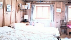 A wooden room with a bed, a small table with a lamp, and a chair. - in Borgonovo by Interhome (Borgonovo)