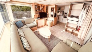 Ein kompakter Wohnbereich mit einer Couch, einem kleinen Esstisch, einer Küchenzeile und einem Schiebetürenschrank.