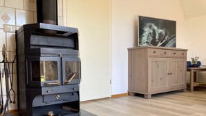 Een moderne keuken met een zwart houtkacheltje, een houten kast en een betegelde achterwand.