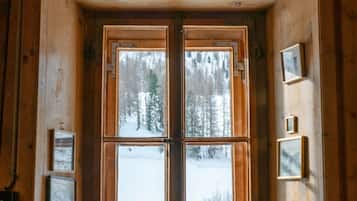 Ein Blockhauszimmer mit großem Fenster, Holzwänden, einer Bank und gerahmten Bildern.
