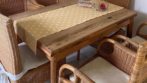 Un coin repas avec des meubles en osier, une nappe à pois et un tableau accroché au mur.