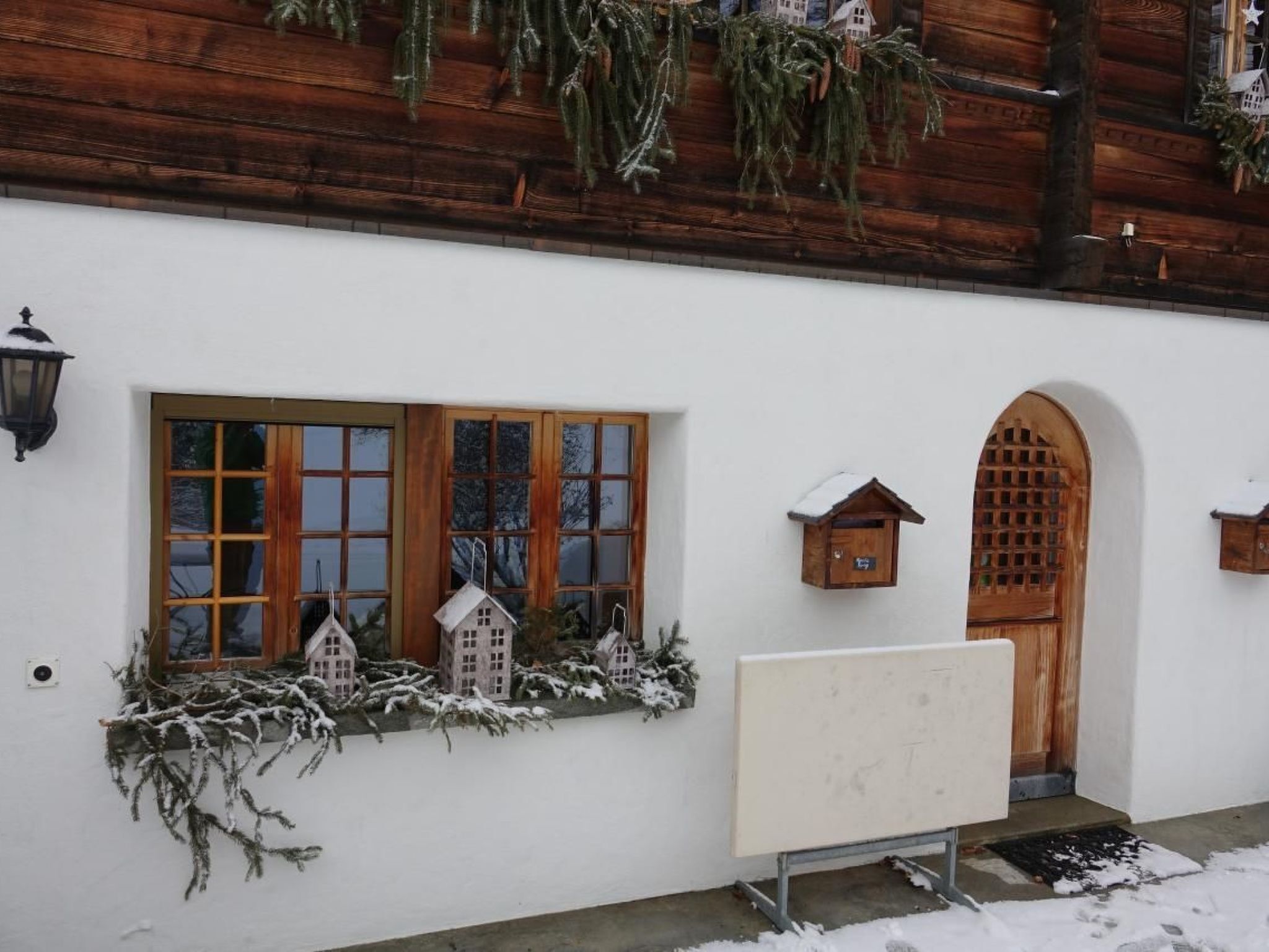 Ein rustikales Gebäude mit großem Fenster, Holztür und kleinen Vogelhäusern.