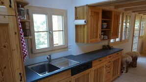 Une cuisine avec des meubles en bois, un évier en acier inoxydable et une fenêtre donnant sur un paysage verdoyant.