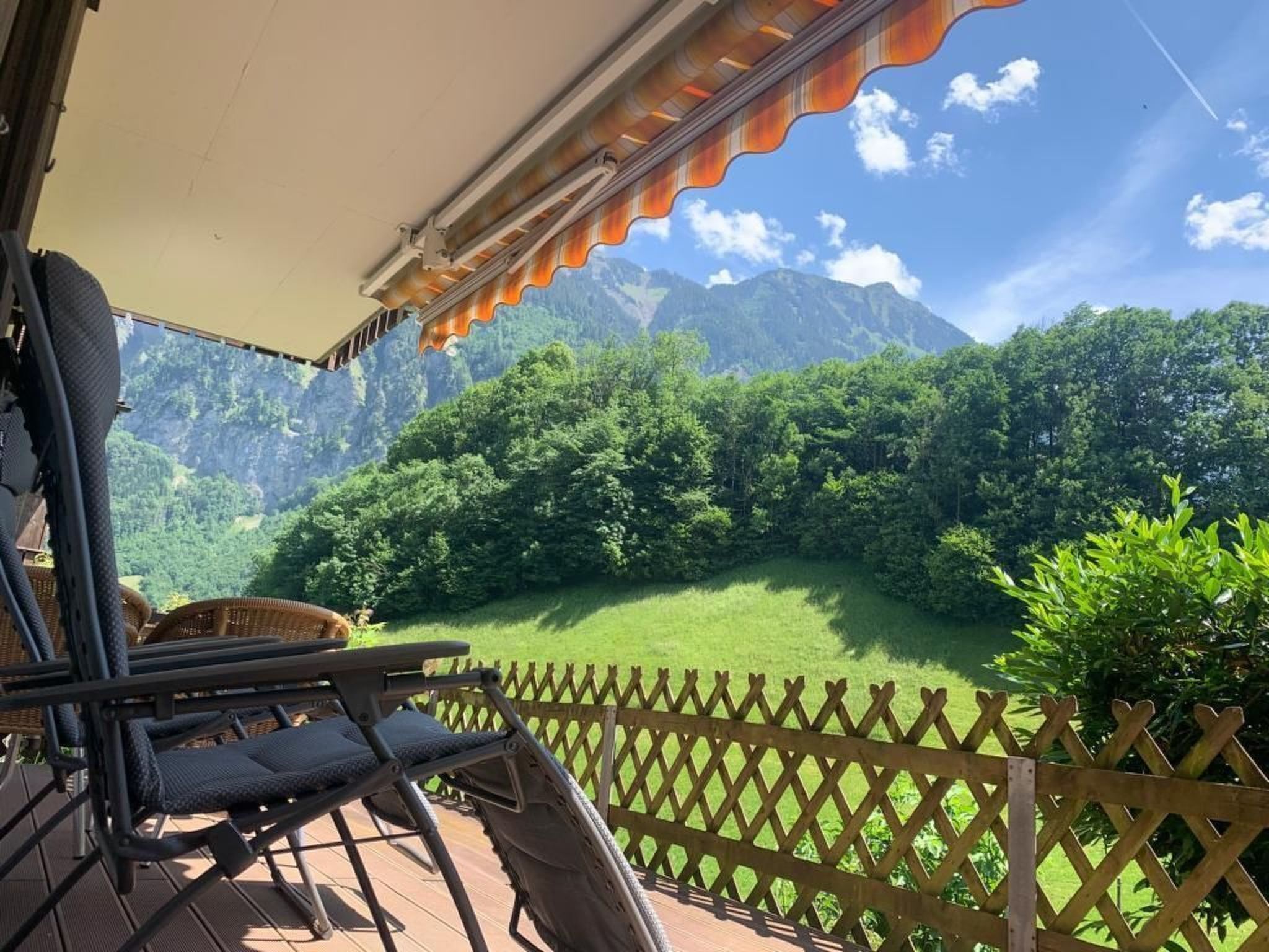 A balcony with a view of a lush green valley and mountains.