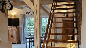 Eine Holztreppe mit Handlauf, die zu einem Bereich im Obergeschoss mit Esstisch und Stühlen führt.