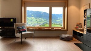 A modern living room with a large window offering a scenic view of green hills. - Ferienhaus Flüeli by Interhome (Flüeli-Ranft)