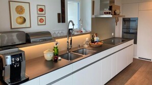 A modern kitchen with a built-in espresso machine, a sink, and a microwave. - Ferienhaus Flüeli by Interhome (Flüeli-Ranft)