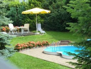 A backyard with a swimming pool, a patio with chairs, and a yellow umbrella. - Martina by Interhome (Auerbach)
