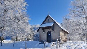 Een laag, eenlaags gebouw met een schuin dak, omgeven door met sneeuw bedekte bomen.