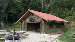 Een vakantiehuis van hout met een rode dakbedekking, een overdekte ingang en een picknicktafel in de buurt.
